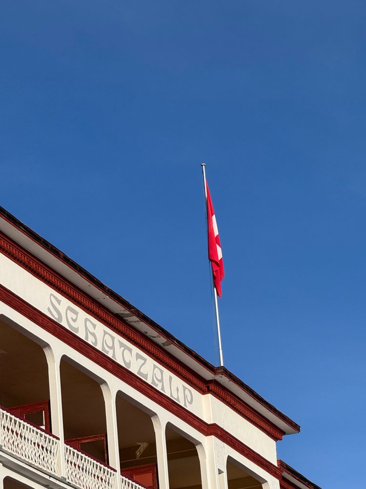Hotel Schatzalp facade in Davos with the Swiss flag against a deep blue sky